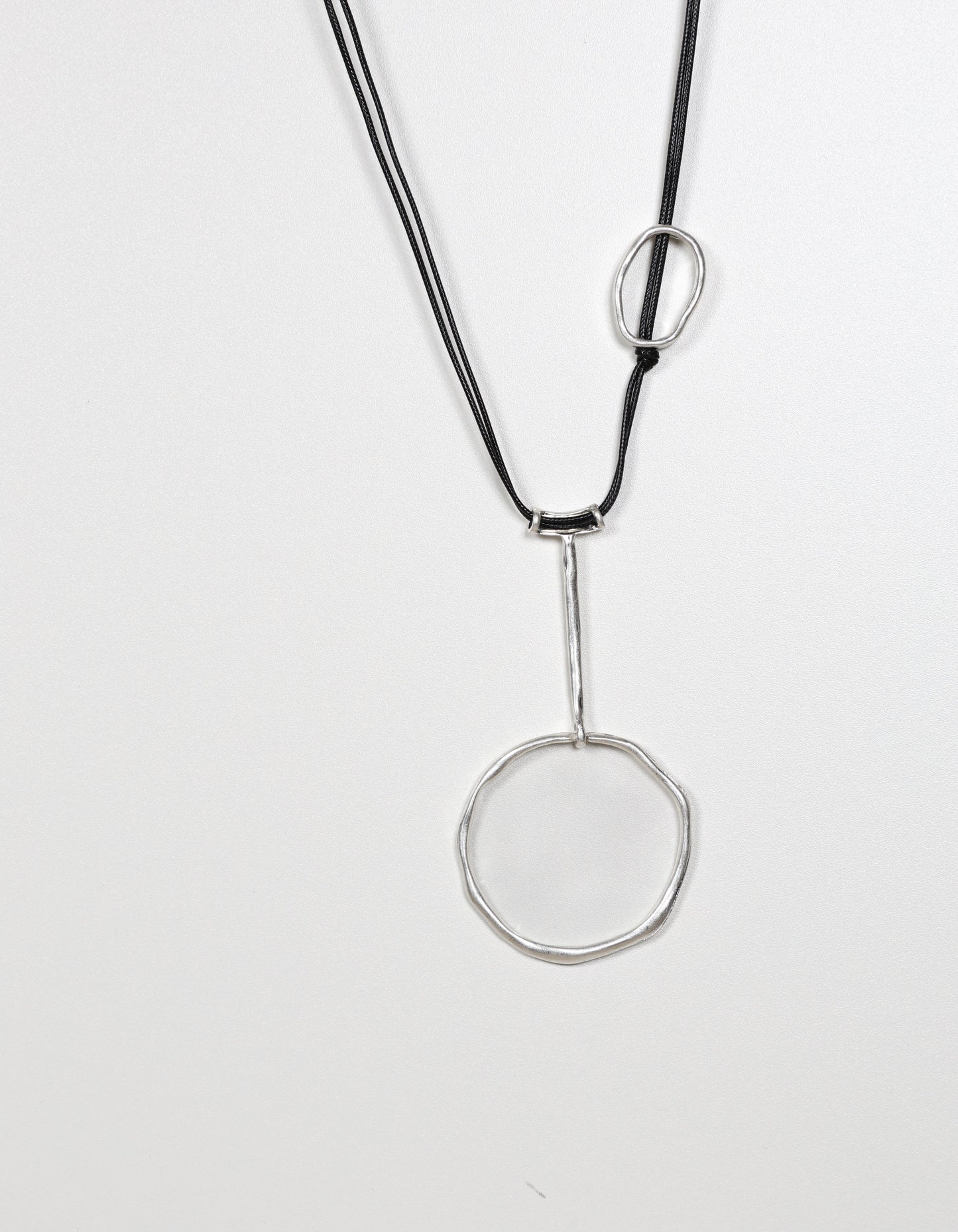 Collier en cordon argenté orné de détails géométriques abstraits en forme de cercle.